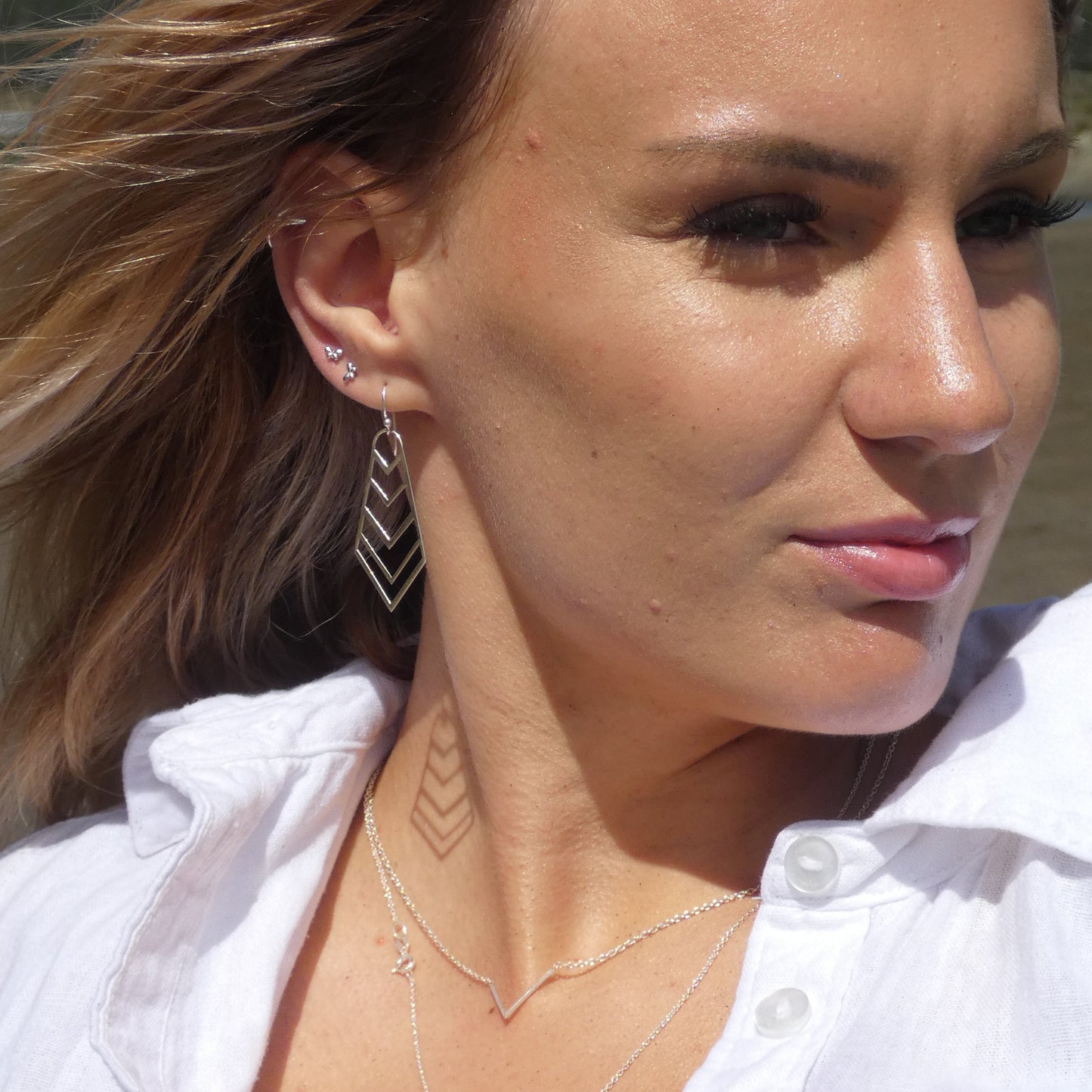 young woman wearing silver geometric drop earrings and necklace